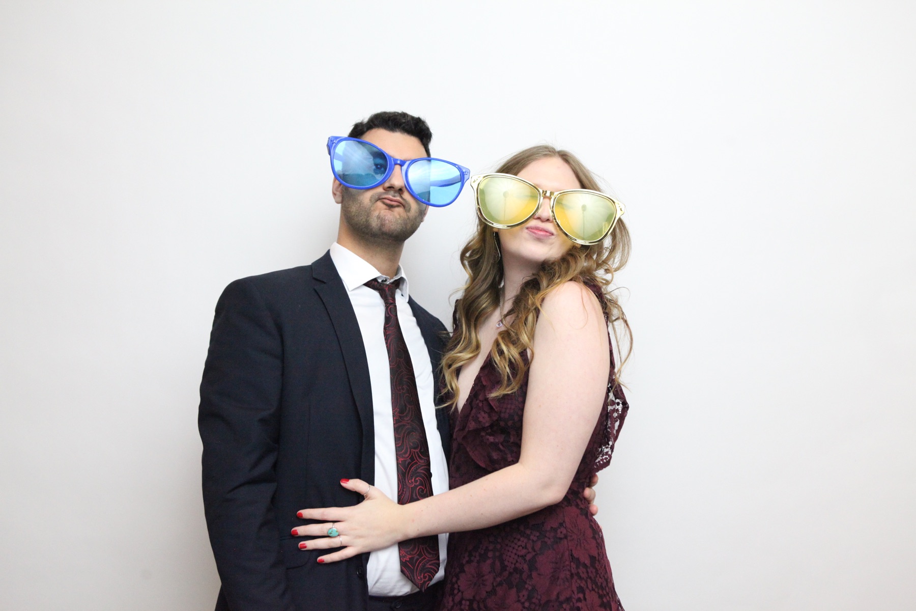 A couple wear oversized sunglasses in the photo booth