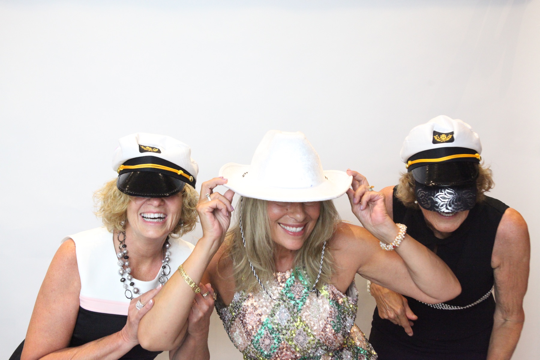 Three guests play with hats