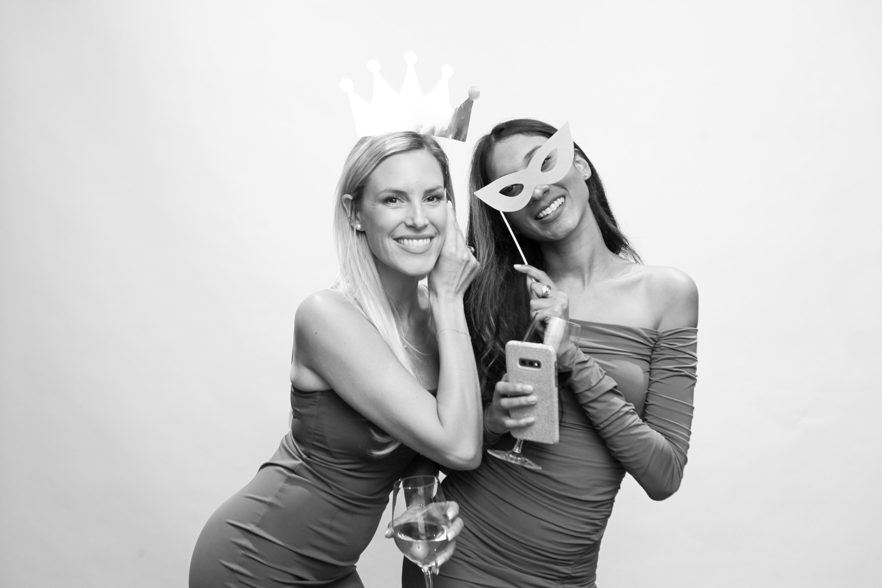 Two friends pose with a crown and mask